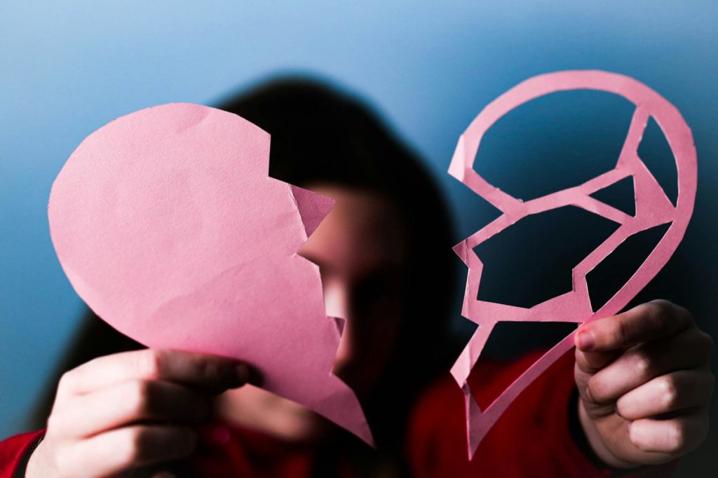 person holding two parts of paper heart